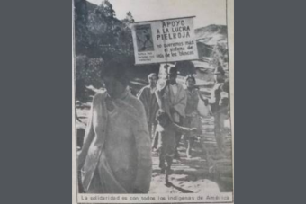 Image of newspaper photo with protestors. One holds a sign that reads  “I support the redskin struggle. We do not want the system of life of the ‘whites’ any longer” in Spanish 